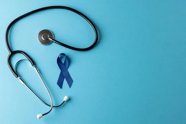 stock image Composition of blue cancer awareness ribbon and stethoscope on blue background with copy space. Medical services, healthcare and health awareness concept.