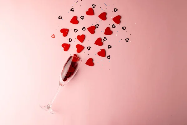 Склянка Шампанського Проливає Червону Форму Серця Конфетті Блідо Рожевому Тлі — стокове фото