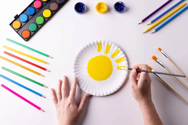 紙皿の上に黄色の塗料で手の絵画のオーバーヘッドは テーブルの上にアート材料と アート 創造性 クラフトマンシップ 趣味のコンセプト — ストック写真