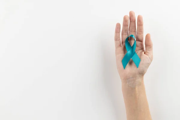 stock image Composition of hand holding blue ovarian cancer awareness ribbon on white background with copy space. Medical services, healthcare and health awareness concept.