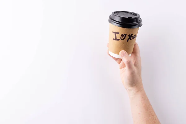 Hand holding takeaway coffee cup with i heart you text written on it, with copy space. Love, romance, taking a break and refreshment concept.