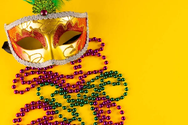 色彩艳丽的杏仁珠和狂欢节的面具在黄色背景与复制空间的组合 庆祝和狂欢节的概念 — 图库照片