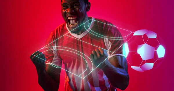 Digital soccer field and ball over cheerful african american male player screaming and shaking fists. Copy space, composite, sport, competition, shape, match, playground, winner, neon, red, abstract.