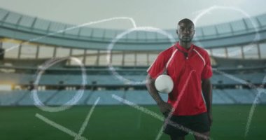 Profesyonel rugby oyuncusu bir spor stadyumunun önünde duruyor.