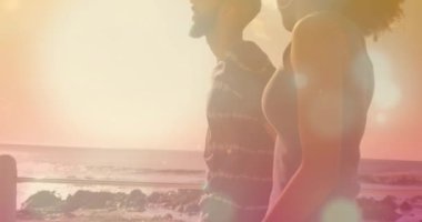 Sahilde yürüyen Afrikalı Amerikalı bir çiftin üzerindeki ışık noktalarının animasyonu. Küresel yaşam tarzı, tatiller ve dijital arayüz kavramı dijital olarak oluşturulmuş video.