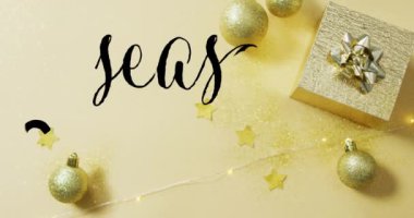 Sarı arka planda yılbaşı süsleri üzerine yapılan tebrik mesajlarının animasyonu. Noel, gelenek ve kutlama konsepti dijital olarak oluşturuldu.