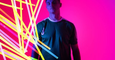 Pembe arka plan üzerinde renkli neon tasarımı olan beyaz genç bir sporcunun portresi. Kopya alanı. Bilgisayar grafiği, dijital kompozit, canlı renk, tasarım, atlet, spor.