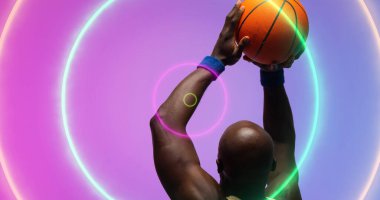 Kel Afro-Amerikan basketbolcu çok renkli dairelerin üzerinden top atıyor. Bileşik, kopyalama alanı, spor, rekabet, illüstrasyon, şekil ve soyut kavram.