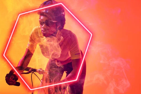 オレンジを背景に自転車に乗る専用のアフリカ系アメリカ人サイクリストの上に六角形のネオン デジタル複合体 スポーツ サイクリング アスリート コピースペース — ストック写真