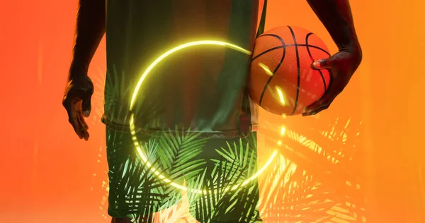 Средняя Часть Африканского Американского Баскетболиста Держит Мяч Освещенными Кругами Растениями — стоковое фото