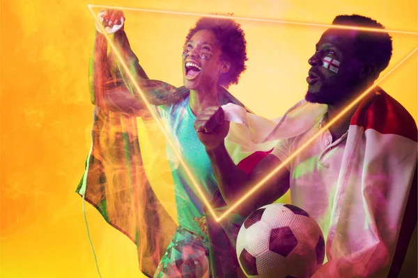 Geometric neon over african american fans with flags celebrating success during soccer match. Digital composite, yellow background, england flag, brazil flag, sport, cheering, spectator, victory.
