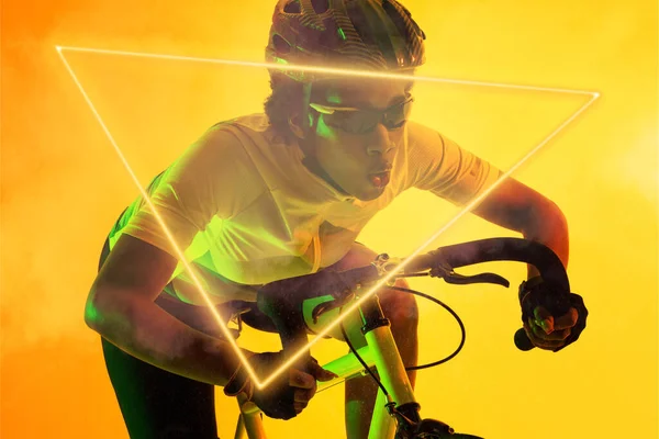 Trójkątny Neon Nad Zdeterminowanym Afrykańskim Kolarzem Jeżdżącym Rowerze Żółtym Tle — Zdjęcie stockowe