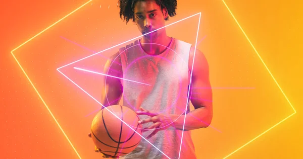 Серьезный Игрок Баскетбол Мячом Стоящим Над Освещенными Несколькими Геометрическими Фигурами — стоковое фото