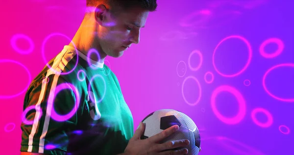 Sammansatt Unga Kaukasiska Spelare Som Håller Fotboll Med Neon Mönster — Stockfoto
