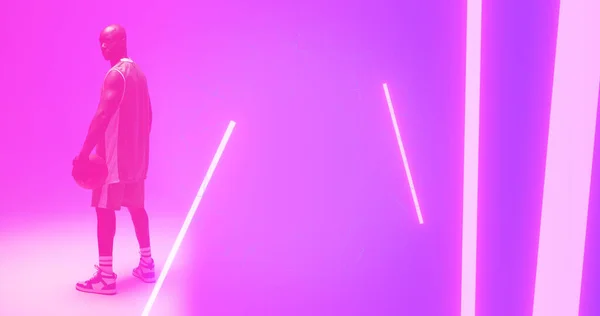 光秃秃的非洲裔美国篮球运动员 球站在粉色背景的灯光下 复制空间 形状和抽象概念 — 图库照片