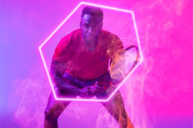 Afrikalı Amerikalı özgüvenli erkek tenisçi, raketi olan, aydınlanmış altıgenin başında duruyor. Boşluğu kopyala, kompozit, spor, rekabet, şekil, duman, çalma, eşleşme ve soyut kavram.