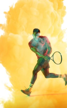 Afrikalı Amerikalı erkek tenisçi raketle koşuyor ve sarı dumanlı arka plana vuruyor. Boşluğu kopyala, kompozit, spor, rekabet, çalma, eşleşme ve soyut kavram.