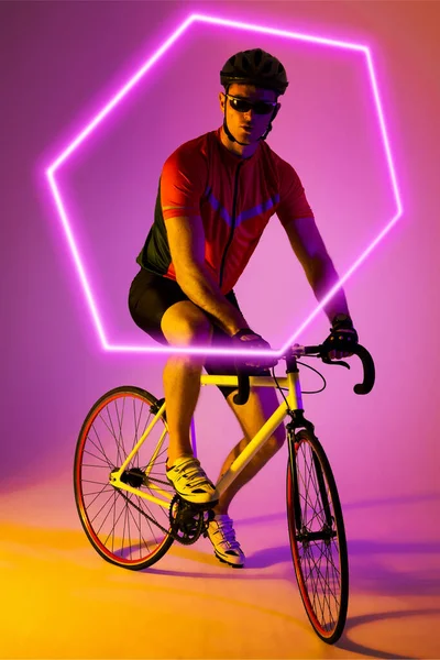 Καυκάσιος Αθλητής Που Κάνει Ποδήλατο Πάνω Από Φωτισμένο Εξάγωνο Φόντο — Φωτογραφία Αρχείου