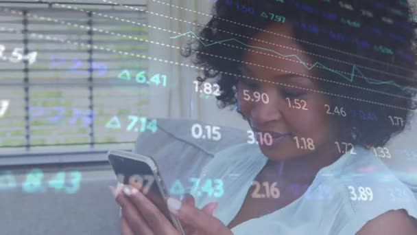 アフリカ系アメリカ人女性が自宅でスマートフォンで話している株式市場データ処理のアニメーション 世界経済とビジネス技術の概念 — ストック動画