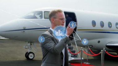 Animation of network of digital icons over caucasian businessman talking on smartphone at airport. Global networking and business technology concept
