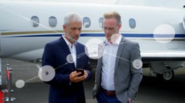 Havaalanında akıllı telefon kullanan iki beyaz iş adamının dijital simge ağının animasyonu. Küresel ağ ve iş teknolojisi kavramı