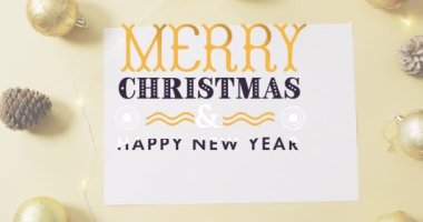 Pembe yüzeyde çam kozalağı, mücevher ve peri ışıklarına karşı mutlu noel mesajlaşması. Noel kutlaması ve yeni yıl kutlaması konsepti