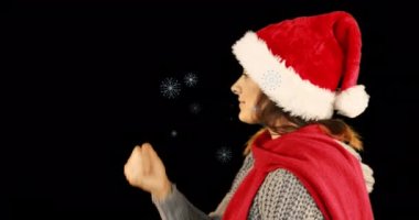 Noel Baba şapkası takan ve kar tanelerine öpücük yollayan mutlu beyaz kadın animasyonu. Dijital kompozit, çoklu pozlama, kış, tatil, Noel, soyut ve kutlama konsepti.