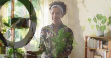Animation of plants over biracial woman potting plant and vlogging. Nature, gardening and leisure time concept digitally generated video.