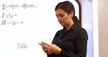 Animation of mathematical equations over caucasian businesswoman using smartphone. Global business, finances and digital interface concept digitally generated video.