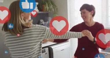 Animation of hearts and like icons over caucasian female couple dancing. Valentines, love and celebration concept digitally generated video.