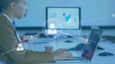 Animation of connected icons in lines on diverse man and woman analyzing reports on laptop in office. Digital composite, multiple exposure, teamwork, communication, business and technology concept.