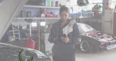 Animation of financial data processing over biracial female car mechanic using tablet. Global business, finance and data processing concept digitally generated video.
