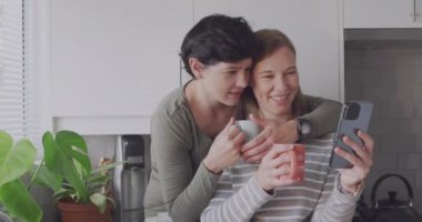 Animation of girl power text over caucasian female couple using smartphone. Valentines, love and celebration concept digitally generated video.