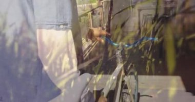 Animation of grass over biracial man walking with bike. Global travel, transport and lifestyle concept digitally generated video.