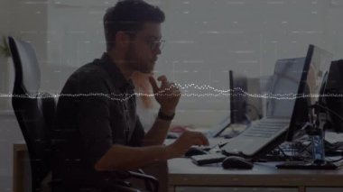 Animation of graphs and changing numbers over biracial man working on laptop in office. Digital composite, multiple exposure, report, business, growth, digits, abstract and technology concept.