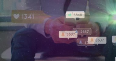 Animation of social media icons with numbers over caucasian man using smartphone. Global social media, technology and digital interface concept digitally generated video.
