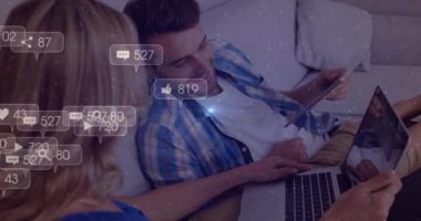 Animation of social media icons with numbers over caucasian couple using laptop. Global social media, technology and digital interface concept digitally generated video.