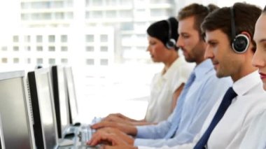 Animation of snowfall over diverse customer service representatives working on computer in office. Digital composite, multiple exposure, call center, teamwork, winter and technology concept.
