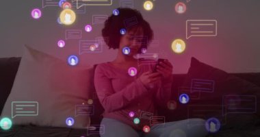 Animation of social media icons with speech bubbles over african american woman using smartphone. Global social media, technology and digital interface concept digitally generated video.