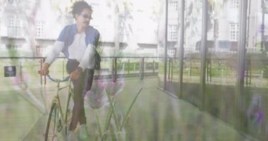 Animation of grass over biracial man riding bike. Global travel, transport and lifestyle concept digitally generated video.