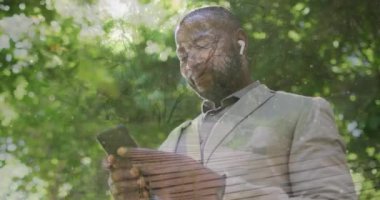 Animation of social media icons with numbers over african american man using smartphone. Global social media, technology and digital interface concept digitally generated video.