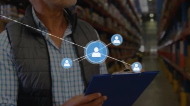 Animation of connected icons on caucasian coworkers checking inventory and writing on clipboard. Digital composite, multiple exposure, warehouse, communication, shipping and distribution concept.