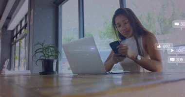 Animation of social media icons with numbers over biracial woman using smartphone. Global social media, technology and digital interface concept digitally generated video.
