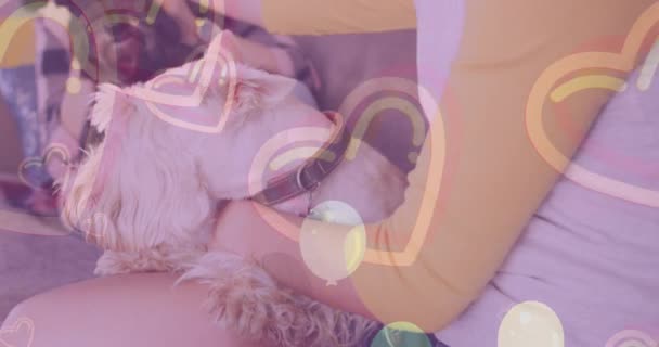 在与他们的宠物狗坐在沙发上的高加索女伴上 心形和气球的动画 情人节 爱情和庆祝的概念数码生成视频 — 图库视频影像