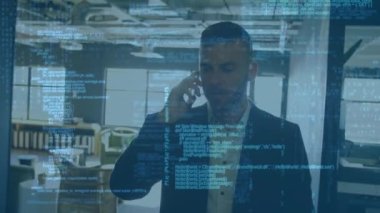Animation of computer language on caucasian businessman talking on cellphone while walking in office. Digital composite, multiple exposure, coding, machine learning, abstract and technology concept.