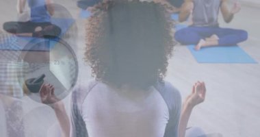 Animation of loading circle and graphs over diverse people practicing yoga in studio. Digital composite, multiple exposure, report, business, progress, numbers, active lifestyle and fitness.