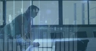 Animation of graphs and buildings over caucasian businesswoman using laptop on desk in office. Digital composite, multiple exposure, meeting, report, skyscraper, abstract and technology concept.