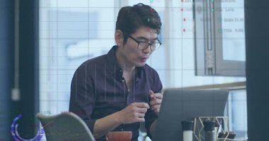 Animation of financial data processing over asian businessman using laptop. Global business, finances and digital interface concept digitally generated video.