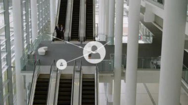 Animation of network of profile icons over aerial view of escalators at modern office. Global networking and business technology concept