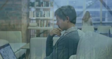 Animation of multiple graphs and leaves over focused caucasian businessman working over laptop. Digital composite, multiple exposure, report, nature, technology, working, professional and office.